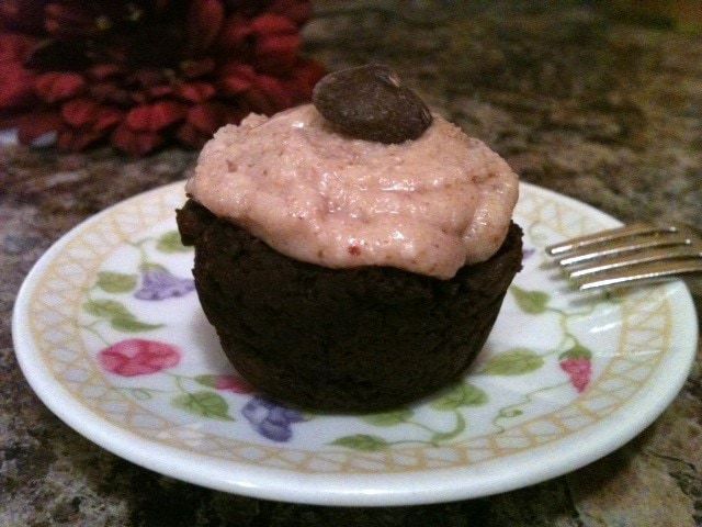 A chocolate cupcake on a plate with a fork.