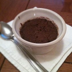 A bowl of chocolate pudding with a spoon on a napkin.