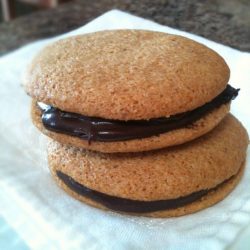 A stack of cookies with chocolate icing sitting on a napkin.