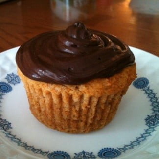 A cupcake with chocolate frosting on a plate.