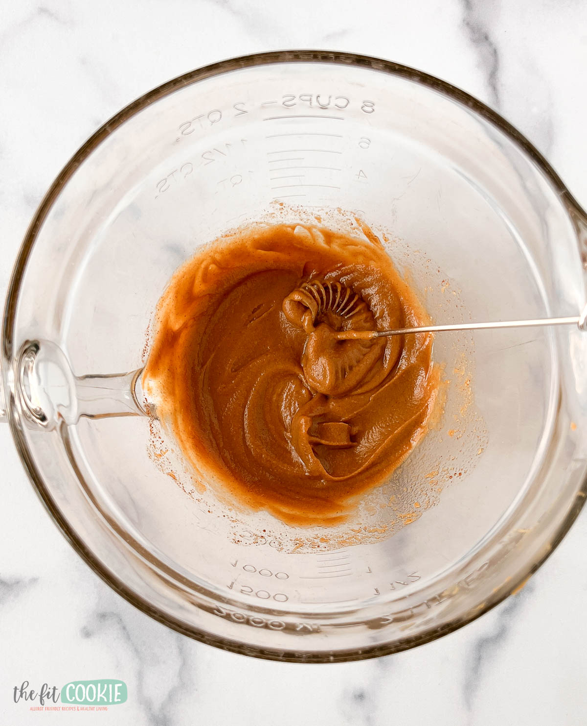 A glass measuring bowl containing maple sunbutter mixture.
