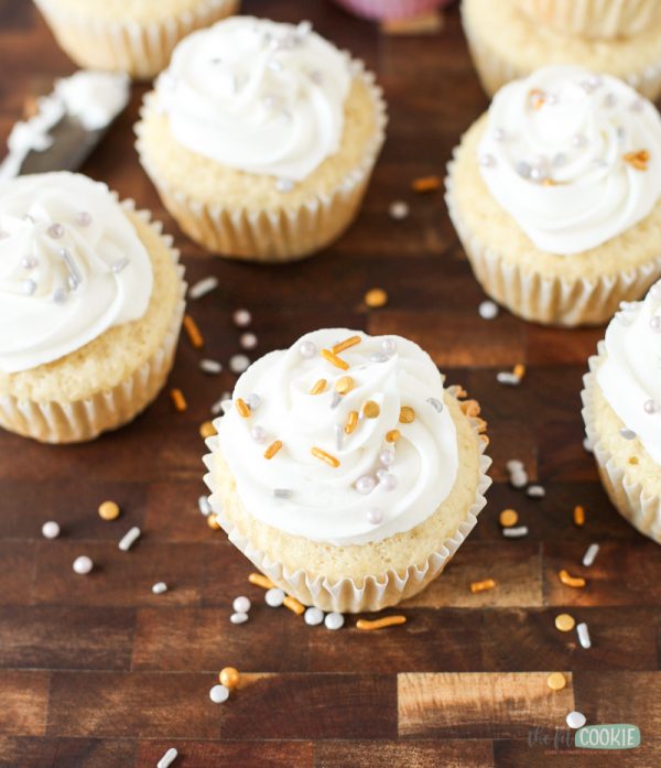 overhead photo of vegan vanilla cupcakes topped with white buttercream and silver sprinkles