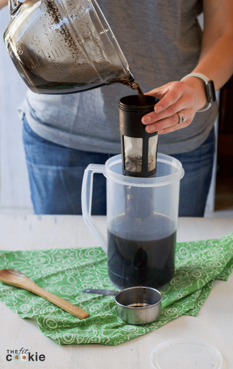 pouring cold brew coffee through filter into a plastic pitcher