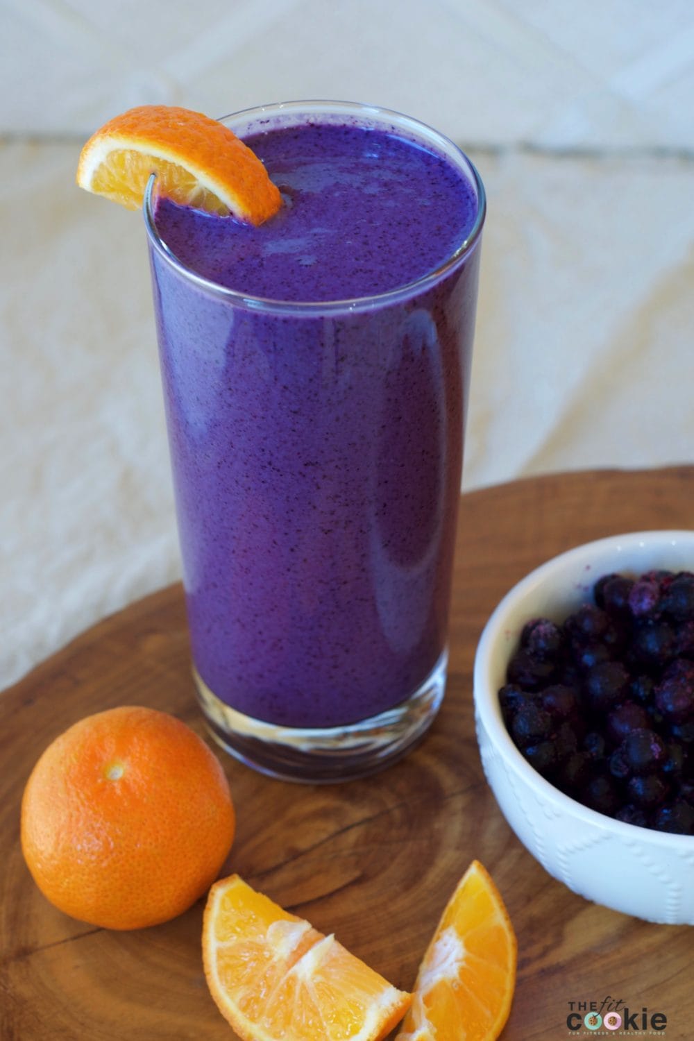A creamy blueberry smoothie with a slice of orange.