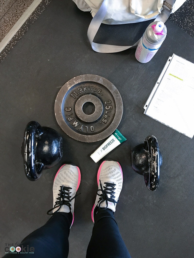 overhead photo of fitness equipment, weights, kettlebells, and Biofreeze for workout recovery