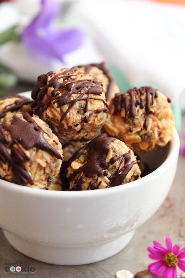 close up photo of energy balls drizzled with chocolate in a white bowl.