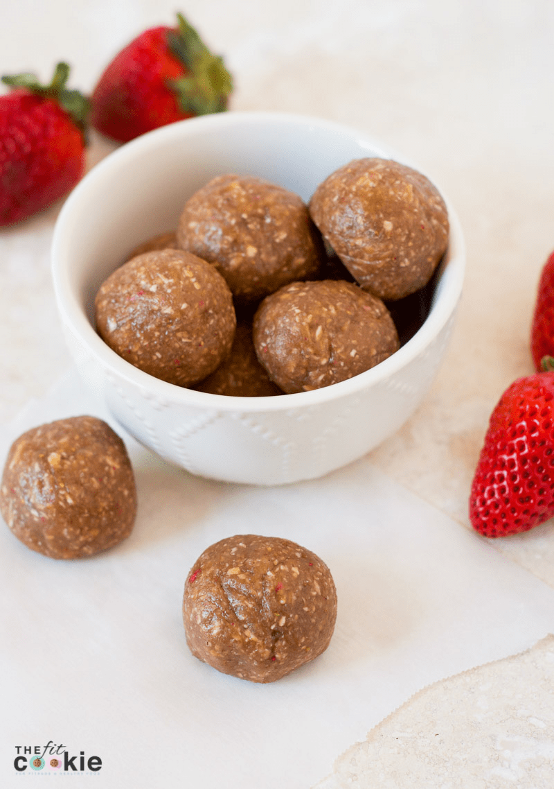 gluten free dairy free strawberry oat protein bites in a small bowl and on parchment paper