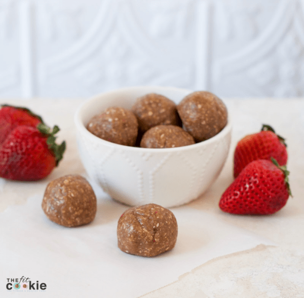 small bowl full of strawberry oat protein bites next to strawberries