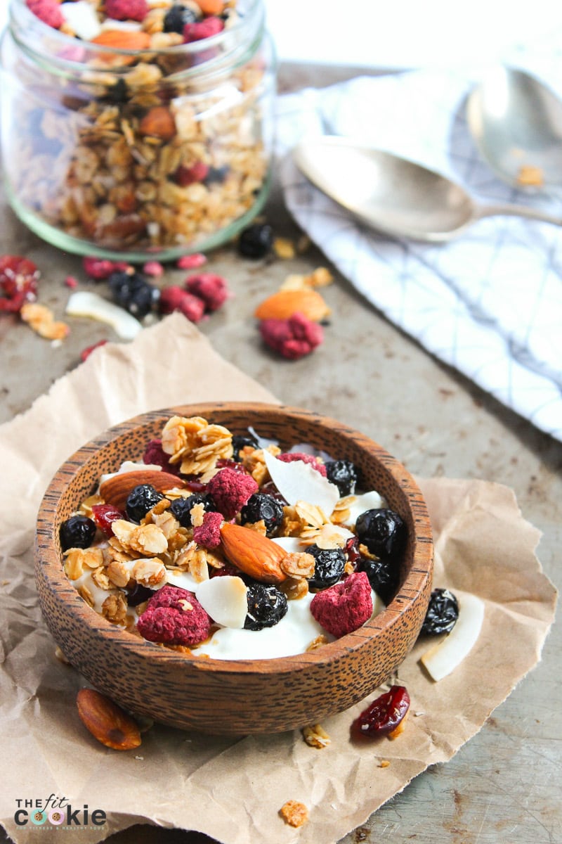 wooden bowl and jar full of gluten free summer berry granola with berries and coconut