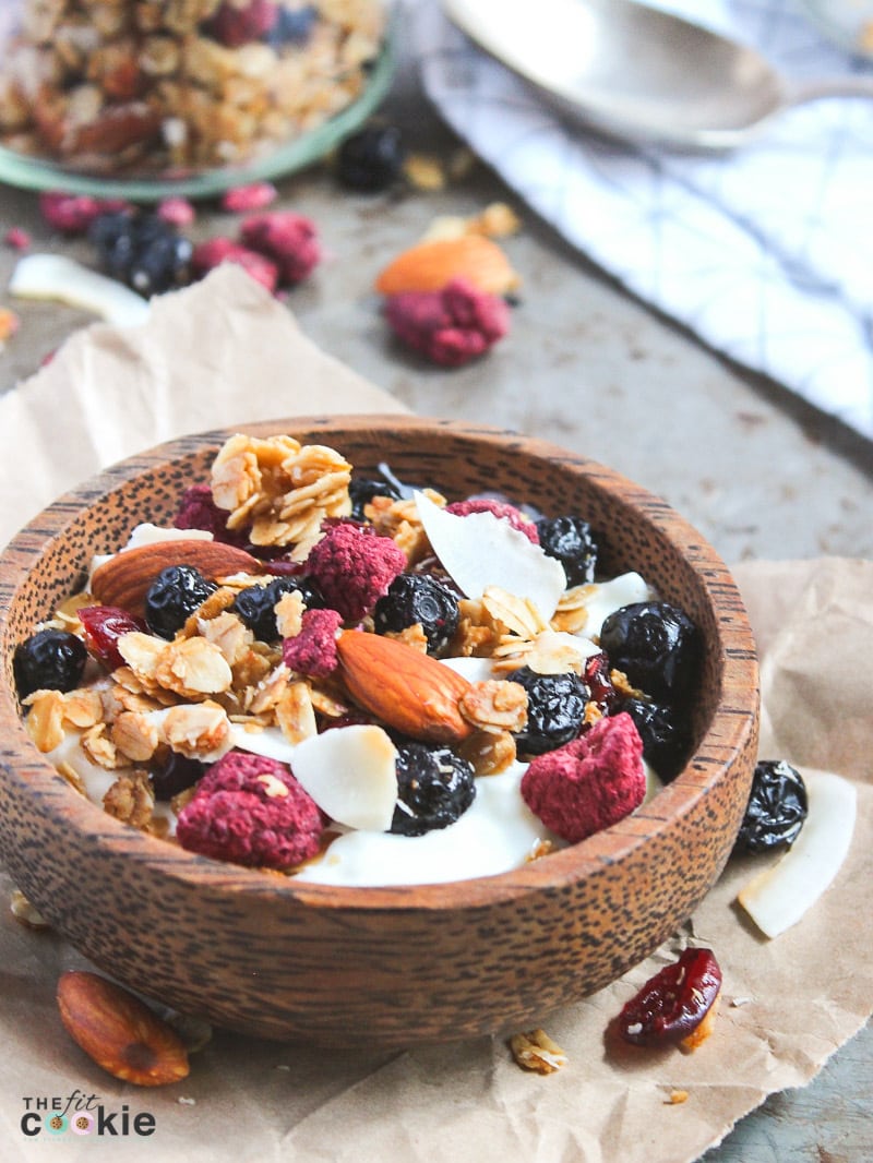 wooden bowl filled with gluten free granola that has dried fruit and almonds mixed in