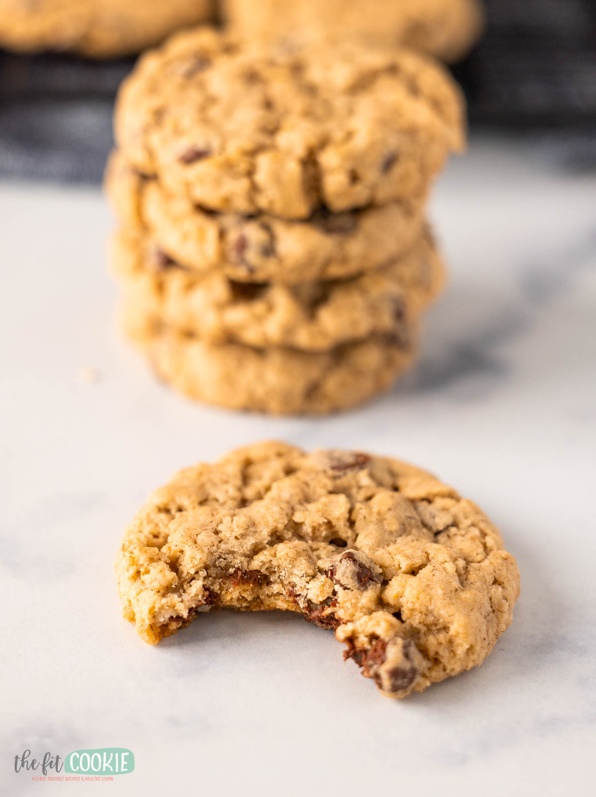A close-up of a vegan oatmeal chocolate chip cookie with a bite taken out of it.