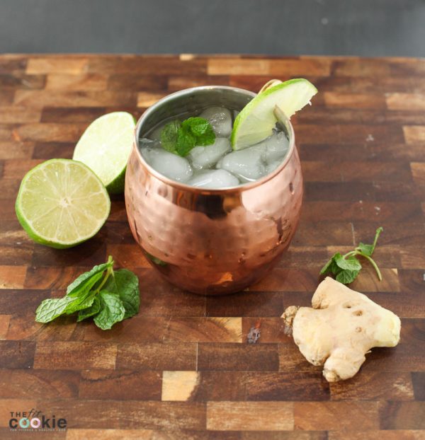 lower sugar moscow mule in a copper mug surrounded by fresh ginger, lime, and mint sprigs