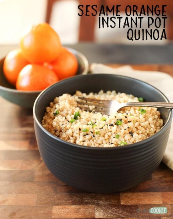 vegan sesame orange pressure cooker quinoa in a black bowl next to mandarin oranges 