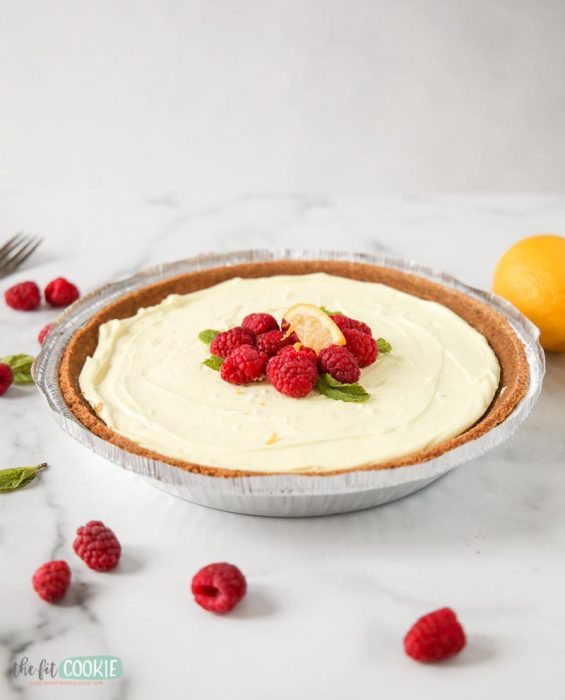 photo of a full vegan lemon cheesecake topped with raspberries and lemon slice