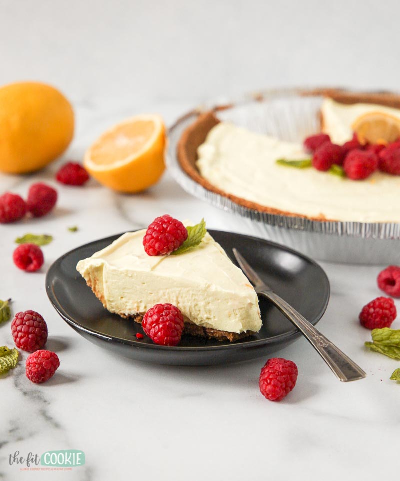 pretty slice of lemon cheesecake on a black plate with a fork