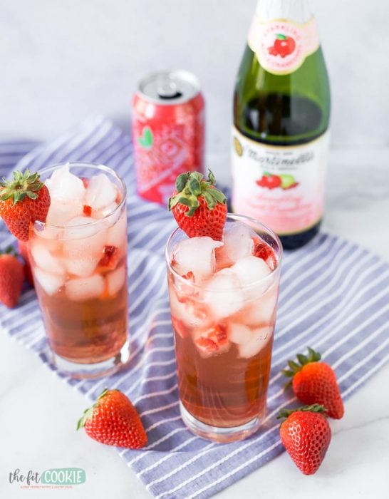 2 glasses of sparkling mocktail on a blue napkin with strawberries
