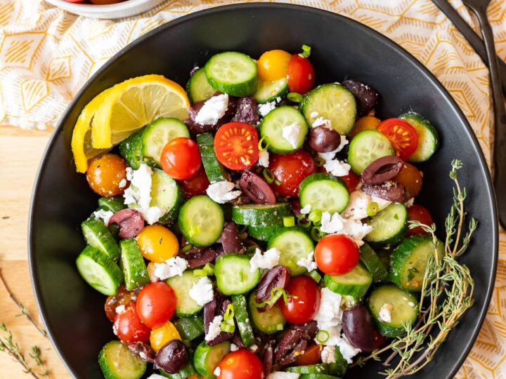 Greek salad with cucumbers, tomatoes and feta cheese served in a black bowl.