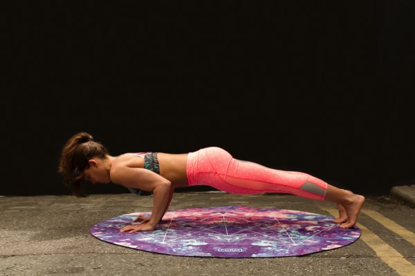 woman doing chaturanga on a yoga mat