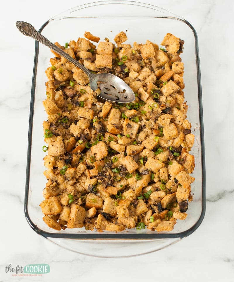 gluten free stuffing in a glass pan with a spoon in it