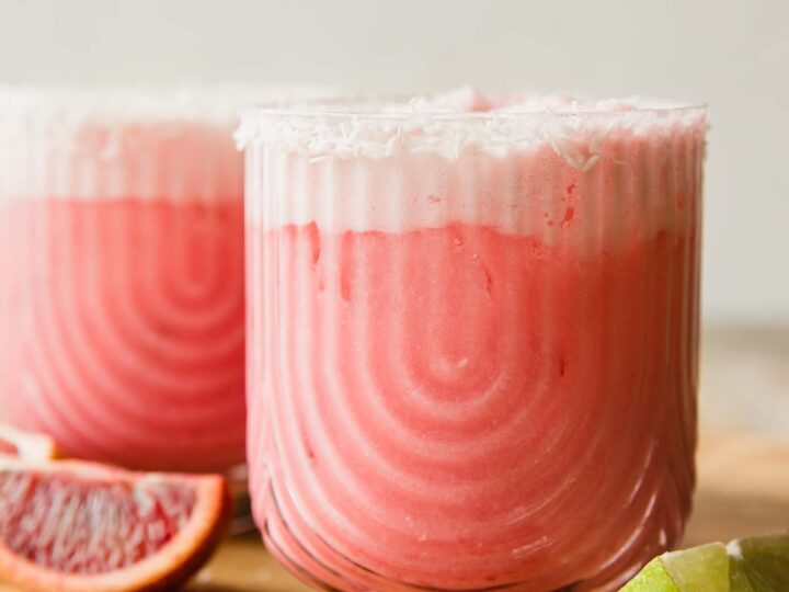 Two glasses of blood orange mocktail on a cutting board.
