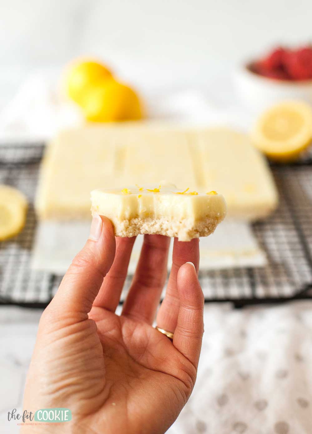 photo of a hand holding a lemon bar with a bite taken