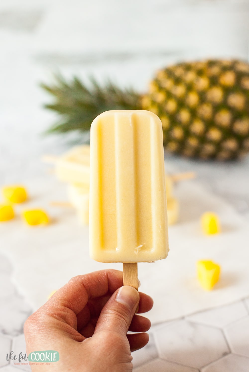 woman's hand holding a pineapple popsicle