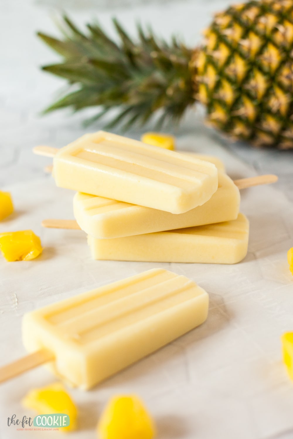 close up photo of popsicles with a pineapple in the background