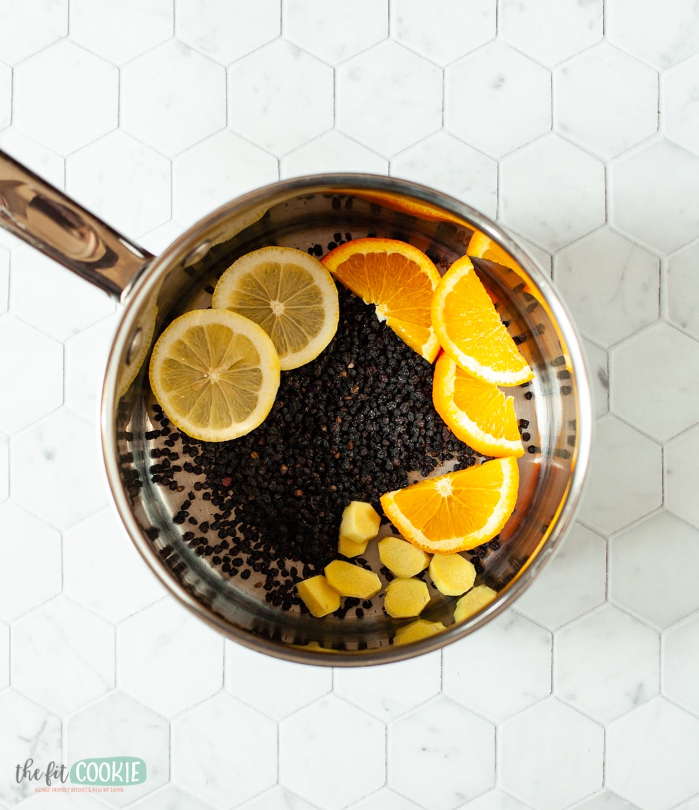 elderberries and orange slices and ginger in a saucepan