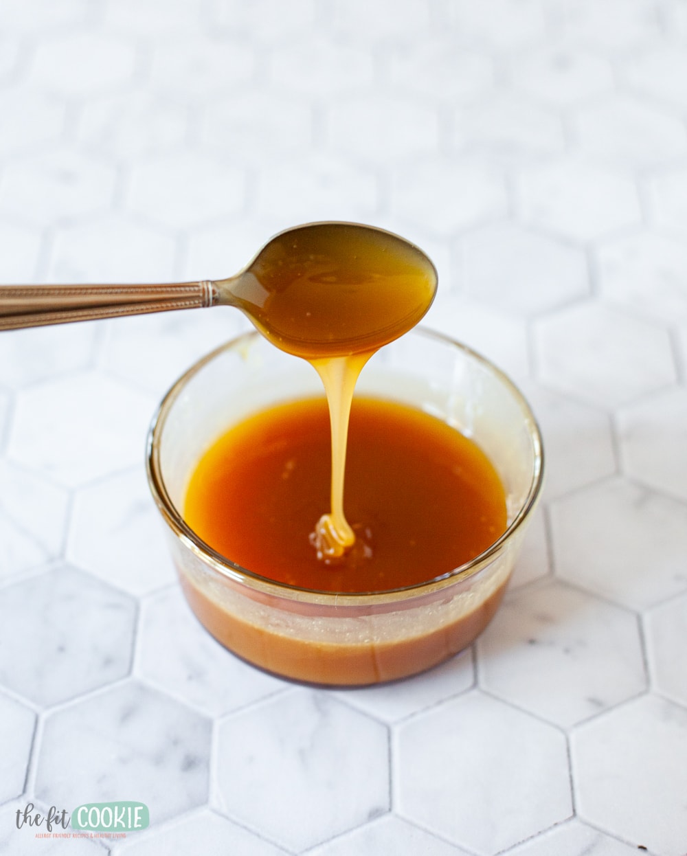 photo of a spoon drizzling dairy free caramel into a small glass dish. 