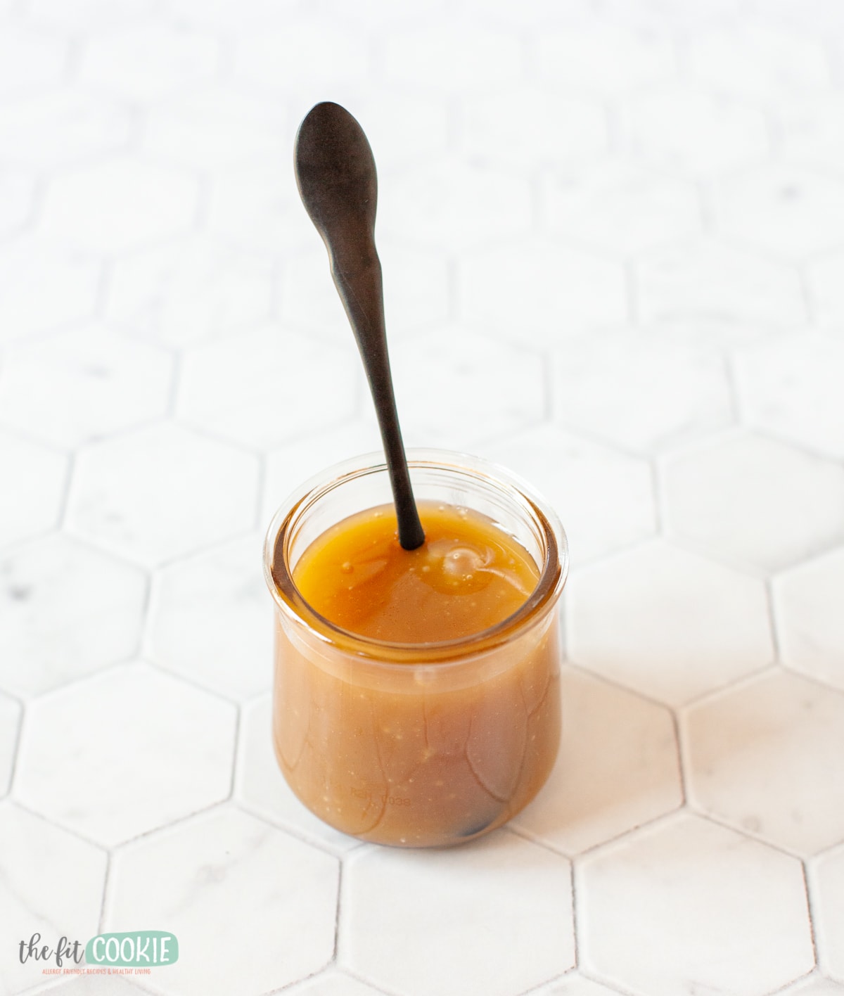 black spoon in a glass jar of dairy free caramel 
