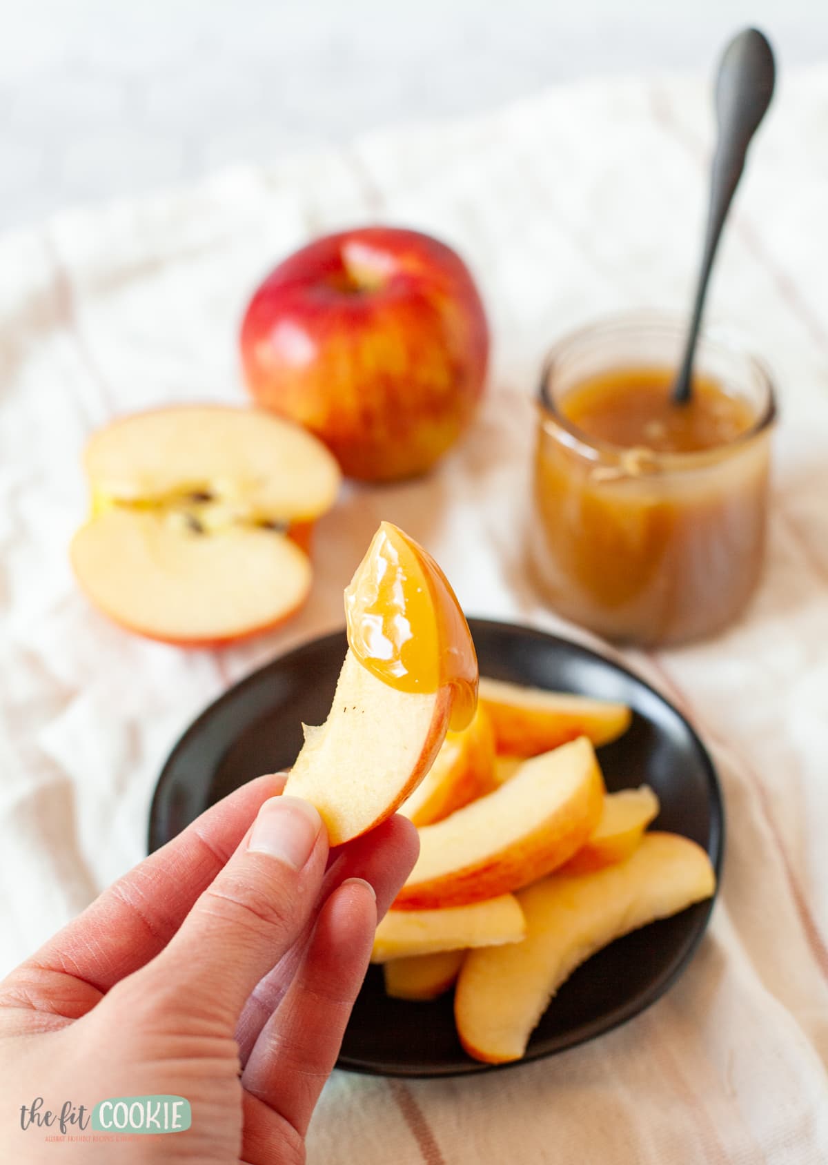 hand holding apple slice with dairy free caramel on it