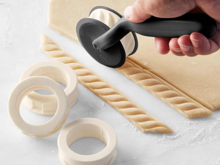 A foodie is using a pastry cutter to make a pastry.