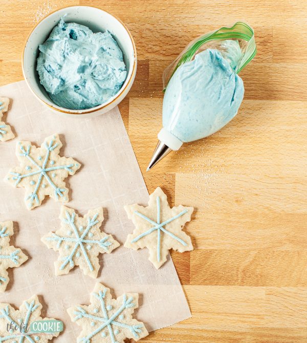 piping blue frosting onto dairy free cut out cookies