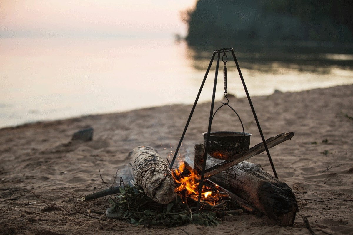 photo of campfire with pot by the lake