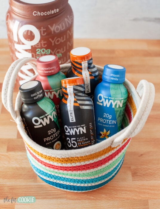 colorful fabric basket filled with bottles of OWYN protein shakes