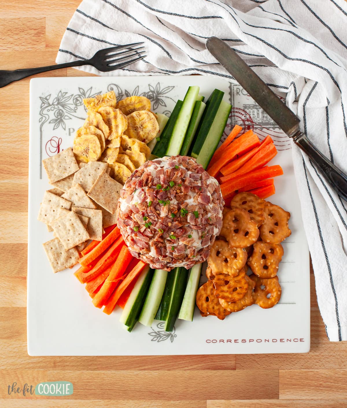 overhead photo of a plate with a cheese ball, crackers, and veggies as an appetizer