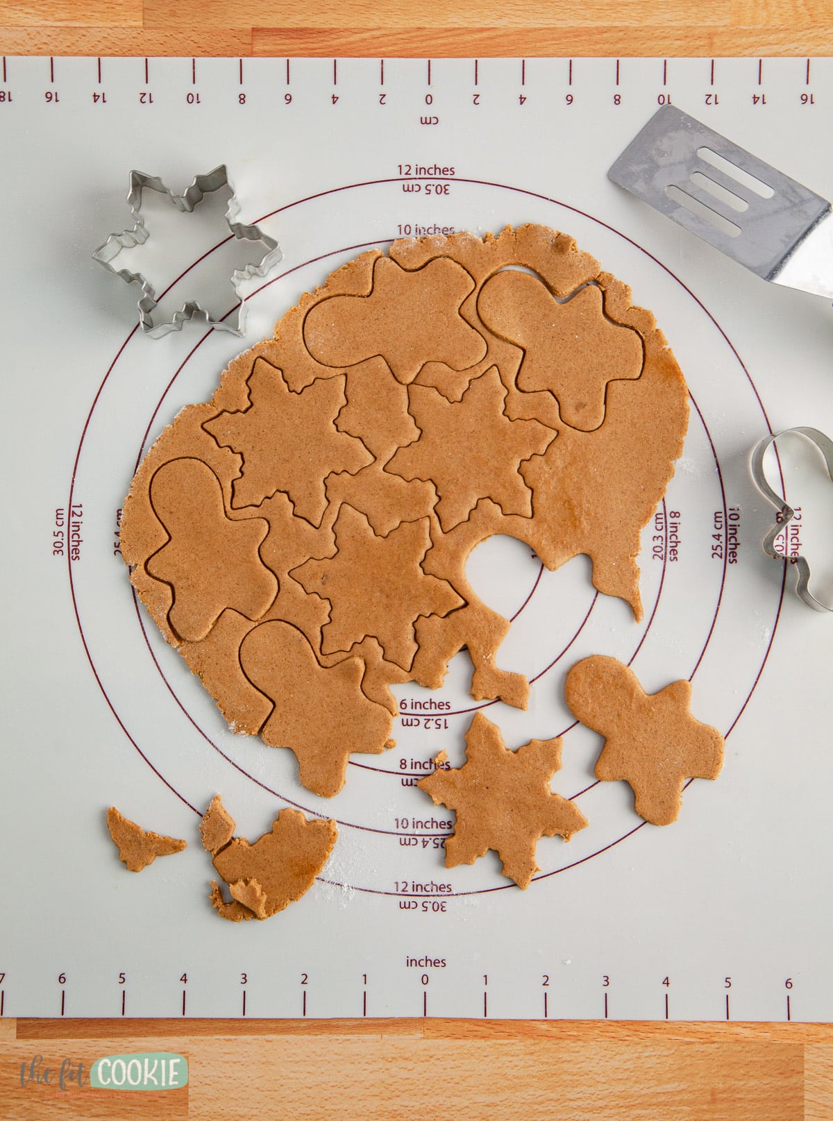 cookie dough rolled out and cut out on a silicone pastry mat