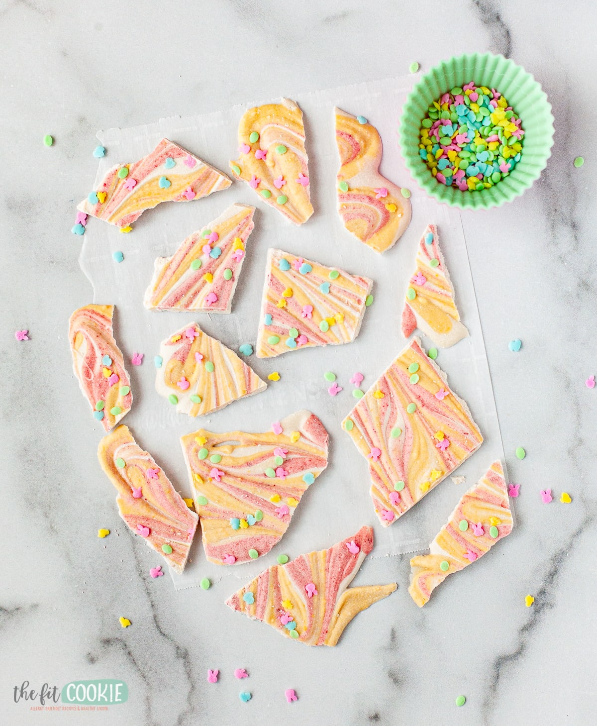 overhead photo of pieces of pastel colored easter chocolate bark on a marble counter. 