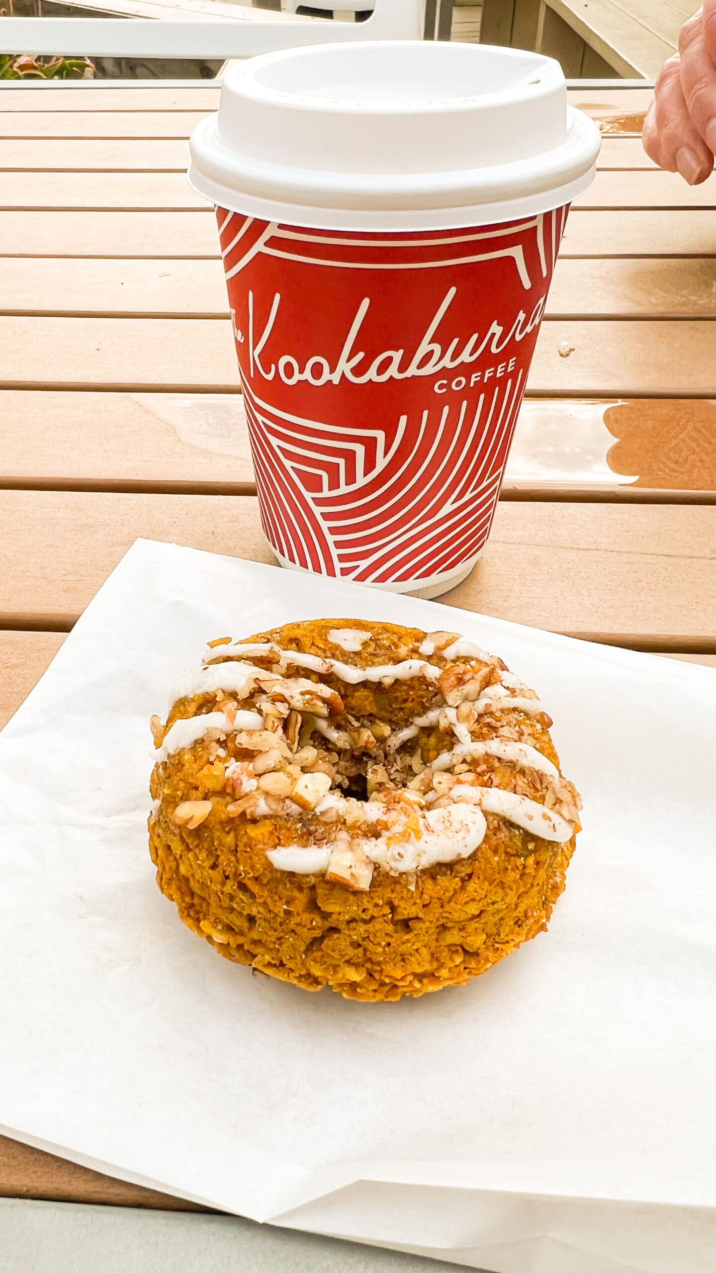 pumpkin donut next to a red cup of coffee from Kookaburra Coffee. 