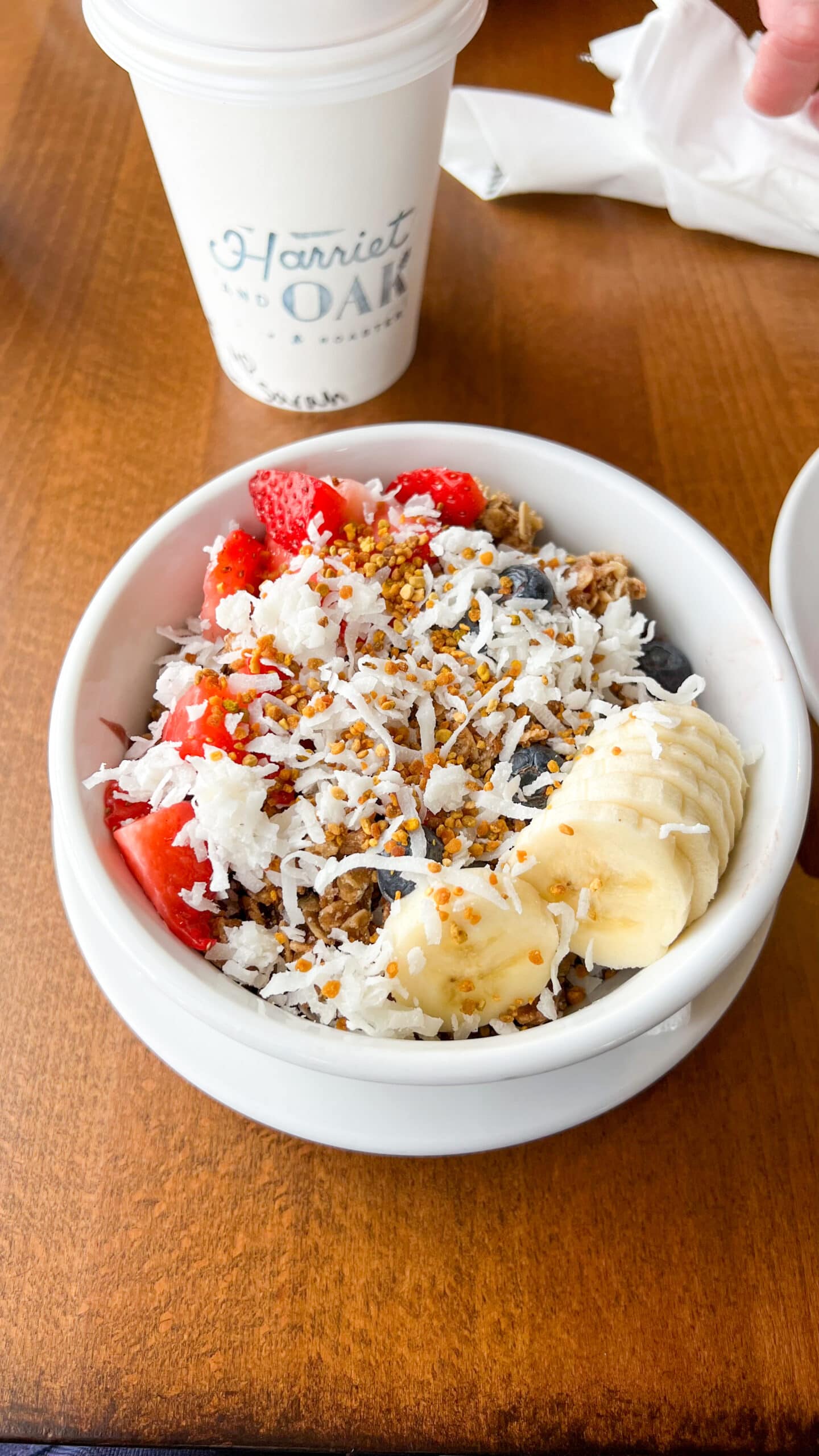 white bowl filled with acai smoothie and topped with granola, bee pollen, fruit, and granola. 