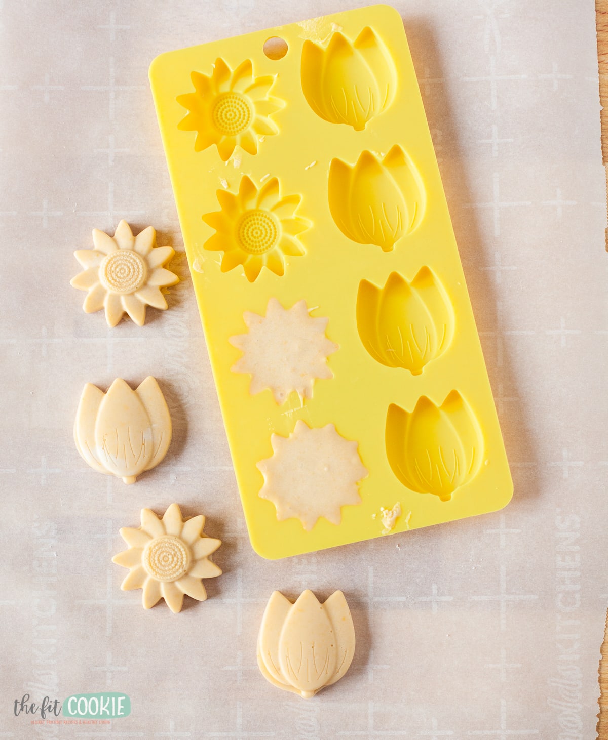 overhead photo of dairy free peach white chocolate flowers next to a yellow silicone flower mold. 