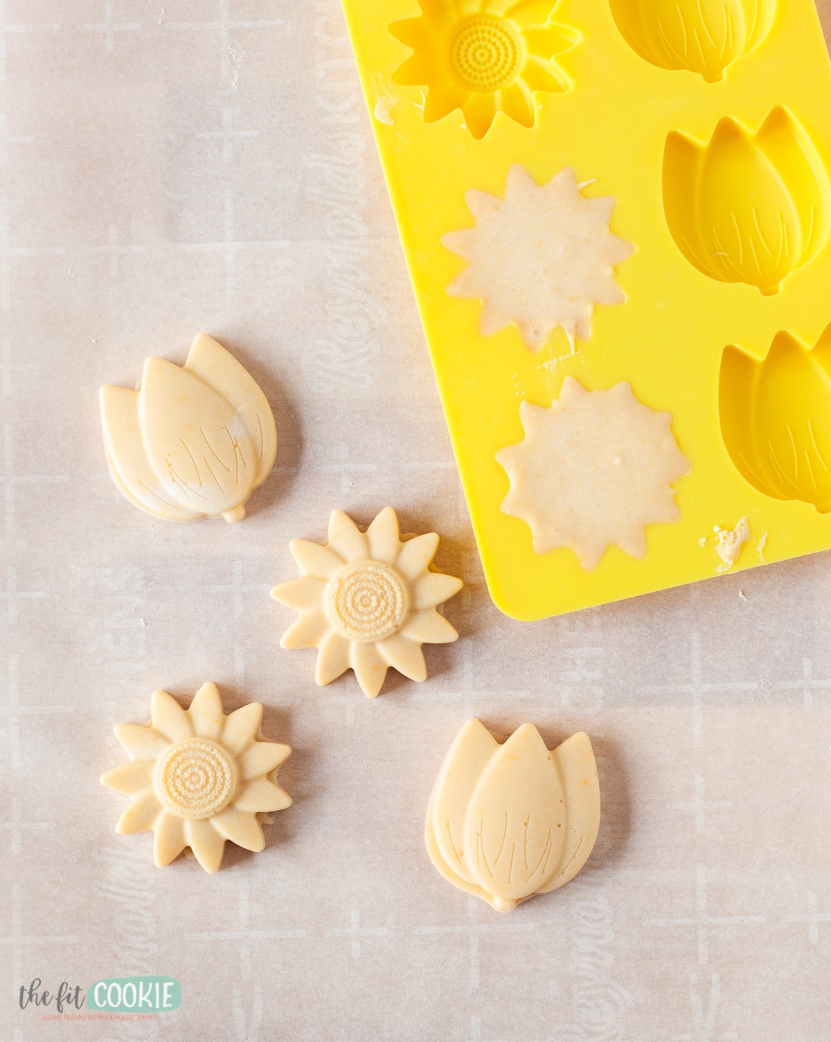 overhead photo of peach and mango white chocolate flowers with a yellow silicone flower mold. 