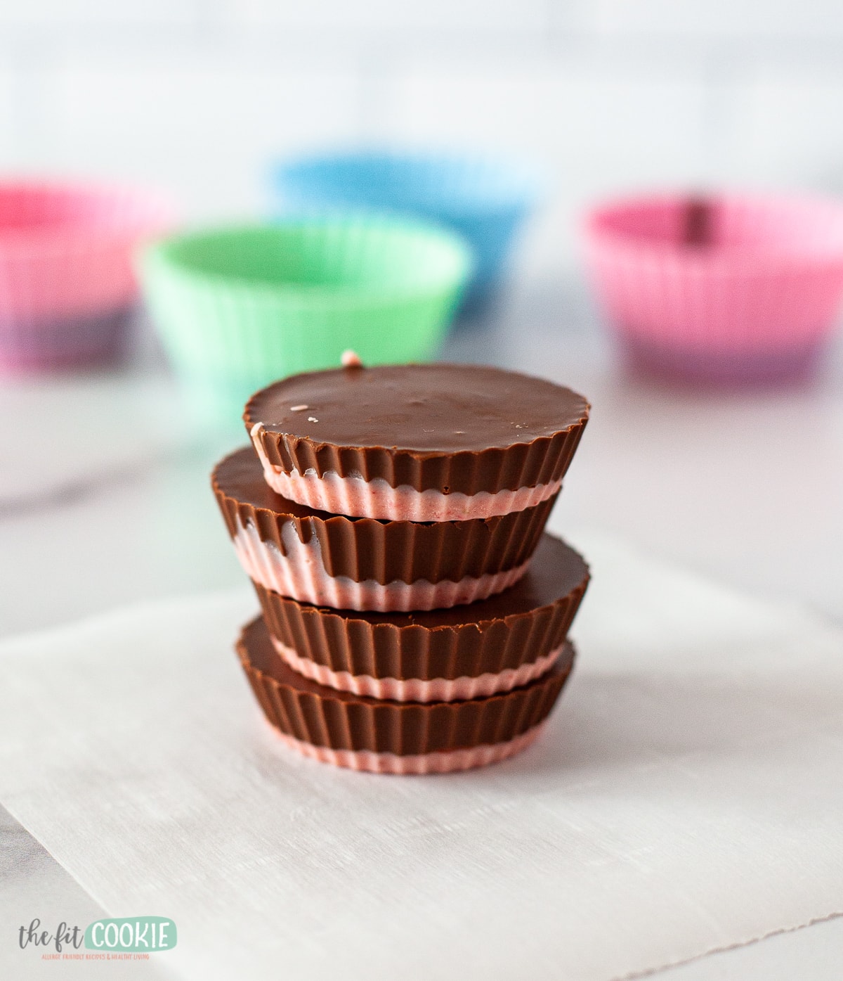 tall stack of chocolate sunbutter cups on parchment paper.