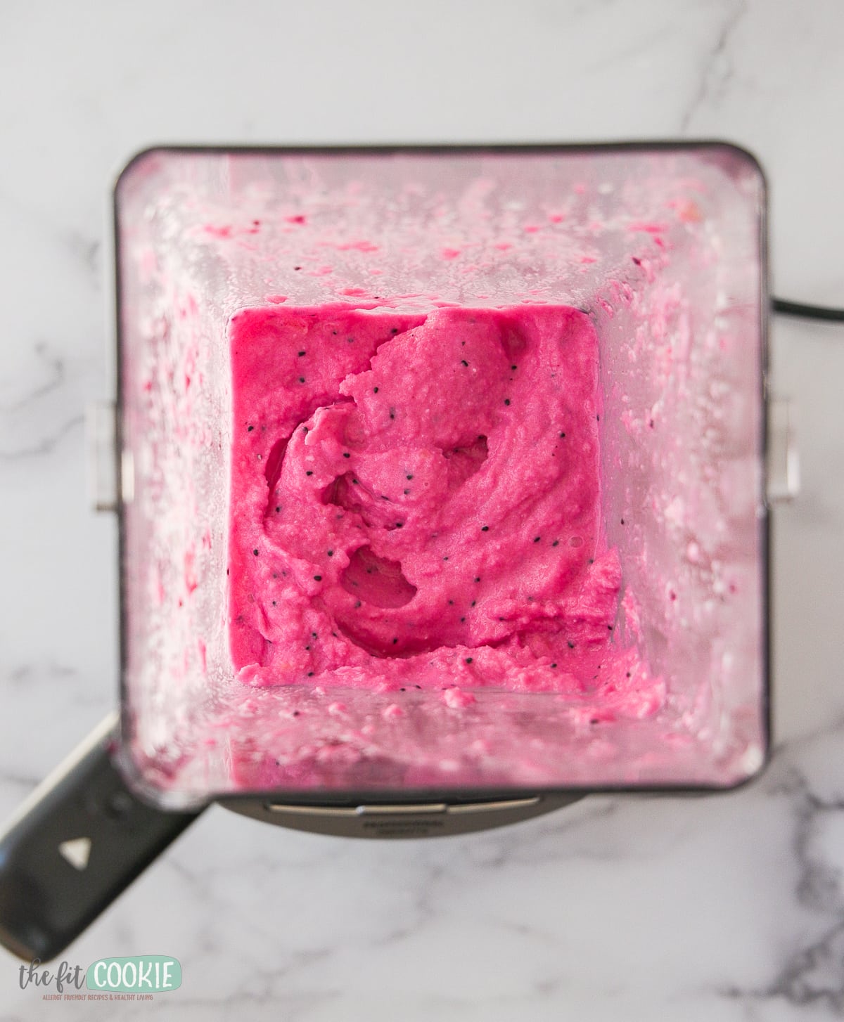 overhead photo of blender container with pink dragon fruit nice cream in it. 