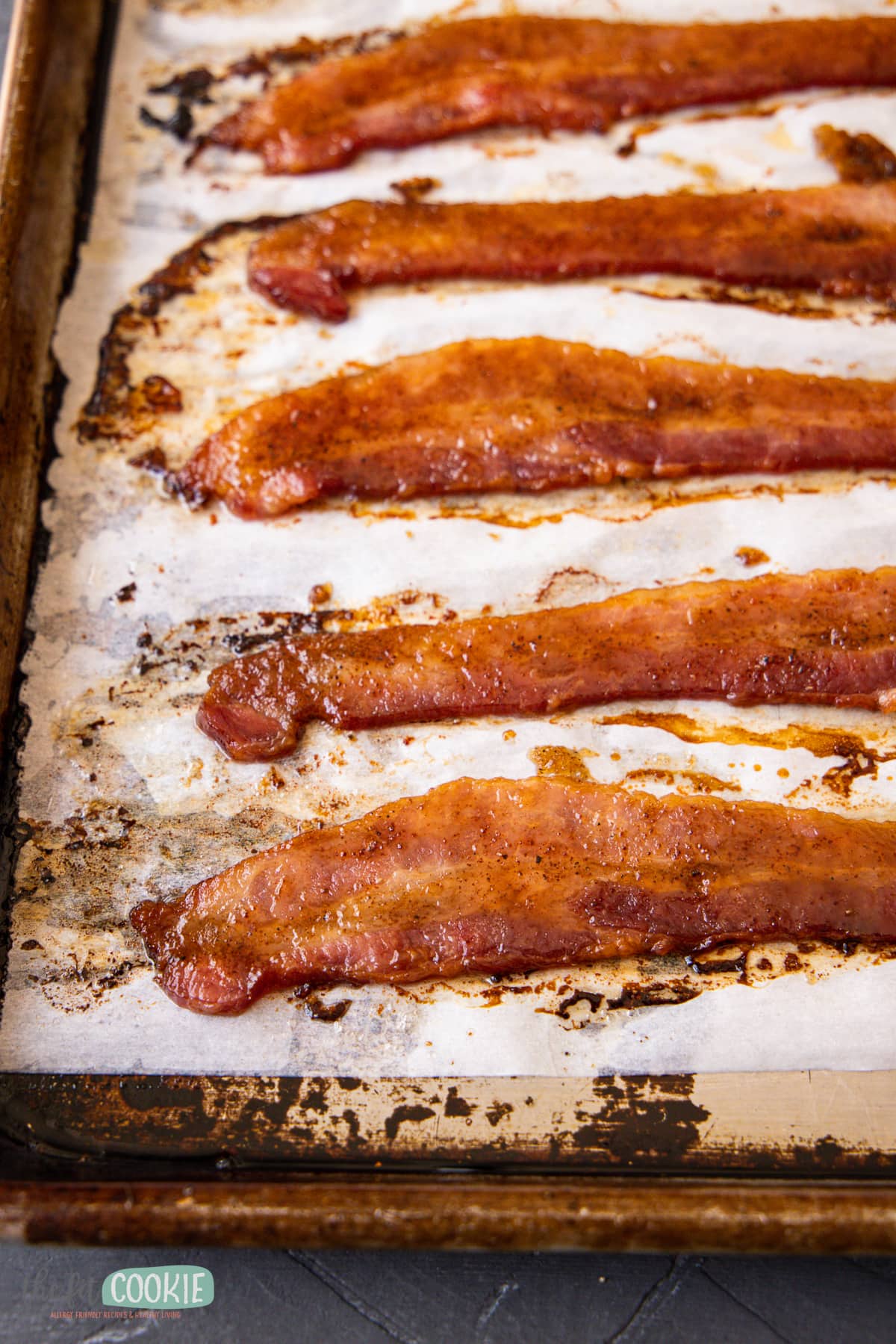 close up photo of brown sugar bacon on a parchment paper lined sheet pan. 