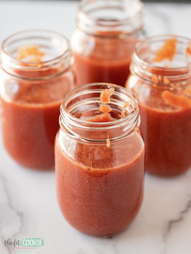 Four jars of tomato sauce on a marble counter.