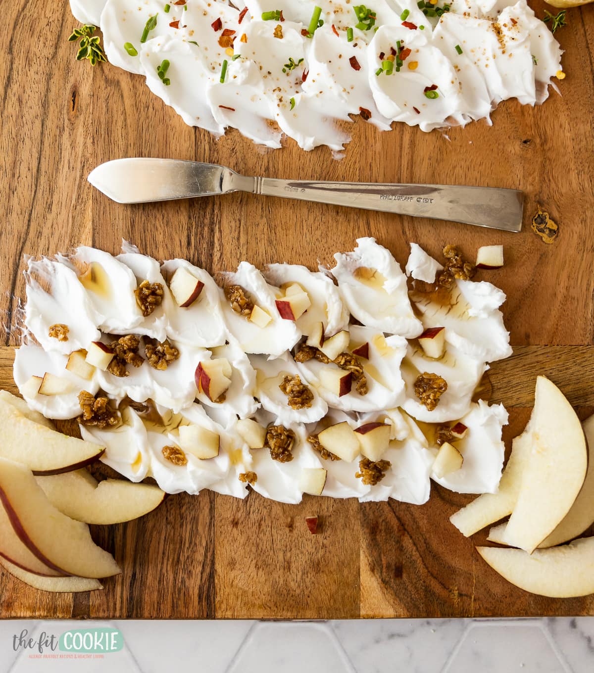 overhead photo of a sweet cream cheese spread on a board, with granola and pears and honey. 