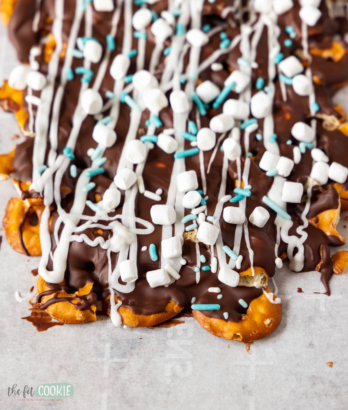 close up photo of candy bark over pretzels with sprinkles and mini marshmallow candies on top. 