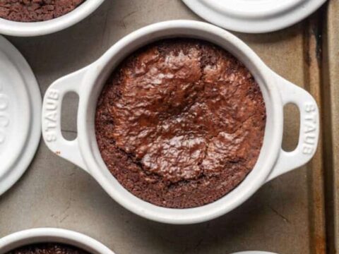 Four white bowls of brownies on a baking sheet.