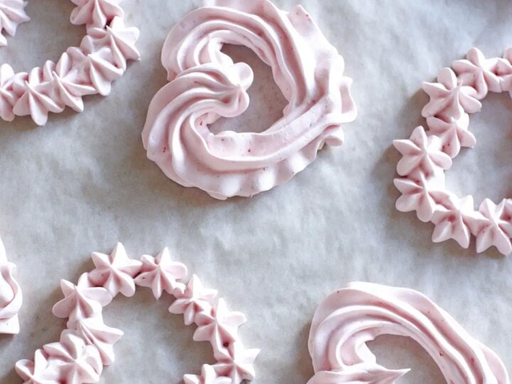 Pink frosted heart cookies on a baking sheet.